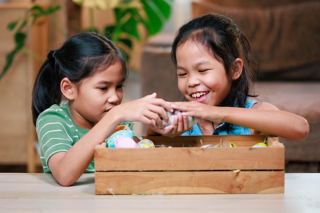 Asian siblings children are playing with baby bunny and decorating easter eggs preparing for Easter at home together with fun Happy family Happy easter Happy holiday