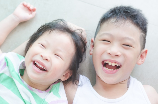 Asian siblings smiling on the floor