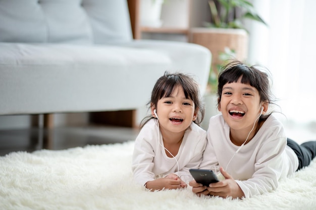 Asian Siblings together on the floor using smartphone