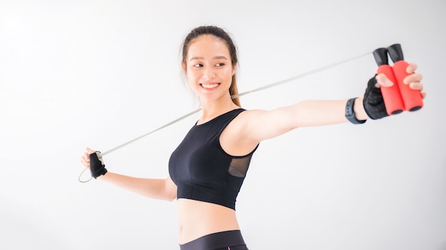 Asian smiling women exercise with jumping rope on white wall fitness background.