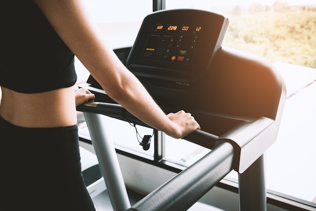 Asian sport woman walking or running on treadmill equipment in fitness workout gym