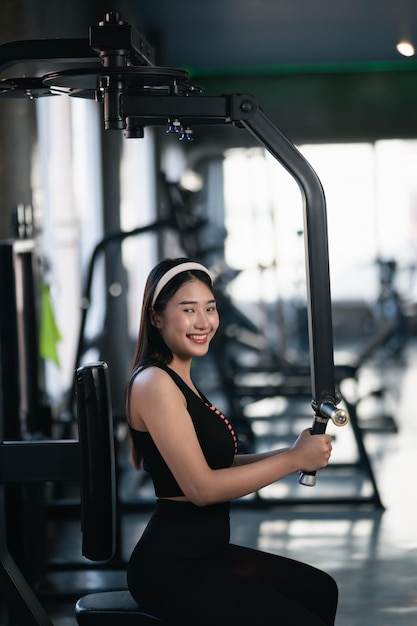 Asian sport women smiling exercise wieght training and workout dumbbell machine training at the gym athlete girl training strong and good health and strength