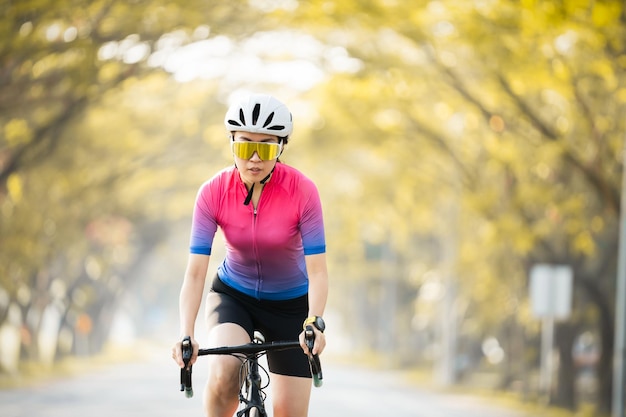 Asian sportive girl rides a bike on the roadcyclist athletes riding a race at high speed on road way