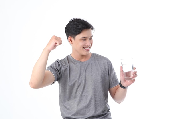 Asian sporty handsome and cheerful young man with a glass of drinking water isolated on background