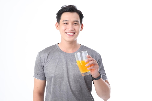 Asian sporty handsome and cheerful young man with a glass of vitamin C orange juice isolated on background