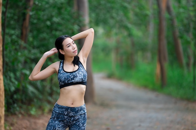 Asian sporty woman stretching body breathing fresh air in the parkThailand peopleFitness and exercise conceptJogging in the parkWarm up body