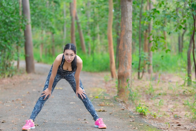 Asian sporty woman stretching body breathing fresh air in the parkThailand peopleFitness and exercise conceptJogging in the parkWarm up body