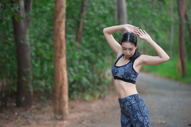 Asian sporty woman stretching body breathing fresh air in the parkThailand peopleFitness and exercise conceptJogging in the parkWarm up bodySit for Lace up shoes