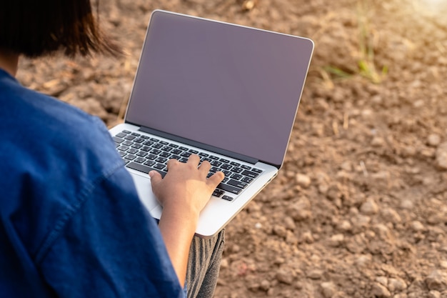 Asian student doing research or checking dry soil in empty land for planting