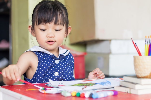 Asian student drawing and painting colours on the paper in the room