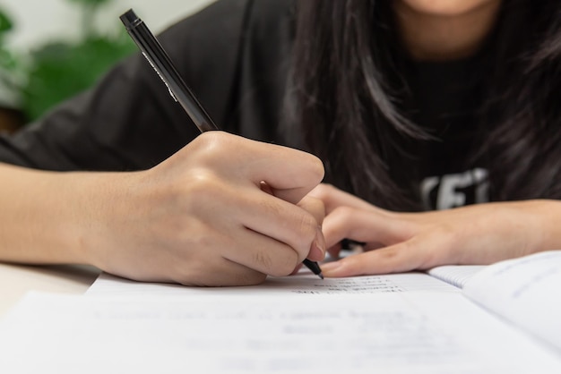 Asian student girl is writing homework and reading book at desk