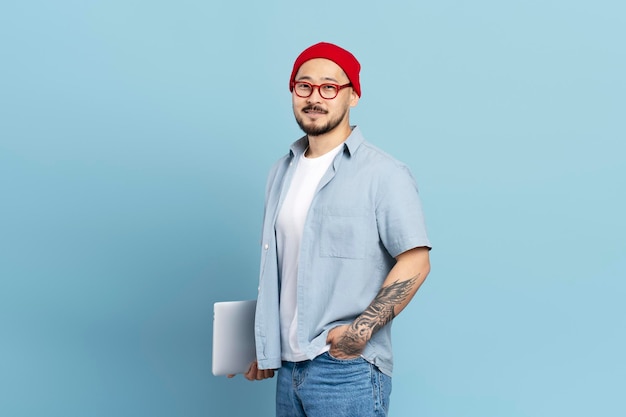 Asian student holding laptop computer isolated on blue background education concept