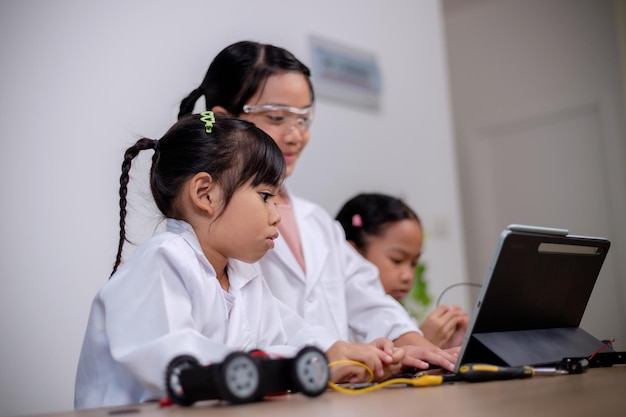 Asian students learn at home by coding robot cars and electronic board cables in STEM STEAM mathematics engineering science technology computer code in robotics for kids' concepts