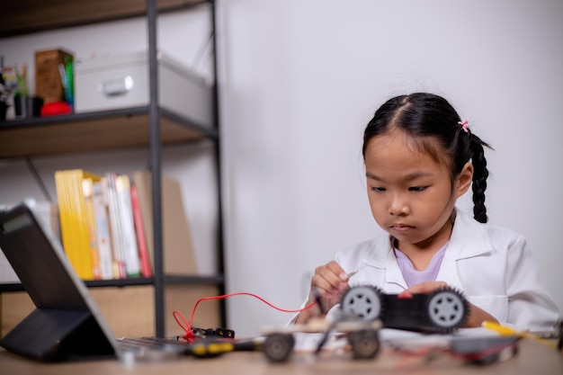 Asian students learn at home by coding robot cars and electronic board cables in STEM STEAM mathematics engineering science technology computer code in robotics for kids' concepts