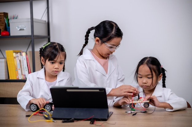 Asian students learn at home by coding robot cars and electronic board cables in STEM STEAM mathematics engineering science technology computer code in robotics for kids' concepts