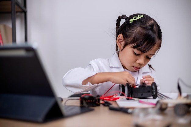 Asian students learn at home by coding robot cars and electronic board cables in STEM STEAM mathematics engineering science technology computer code in robotics for kids' concepts