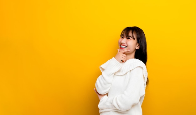 Asian teenage girl feeling happy. smile and look up Relax in the photography room at his home. with free space on a yellow background