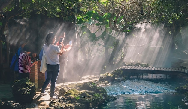 Asian tourists using their mobile phone to taking picture of nature in tropical garden