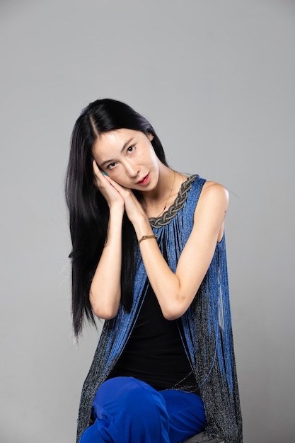 Asian Transgender Woman with long black straight hair look at camera Female sit and wear blue fashion sensual sexy dress gray background isolated copy space