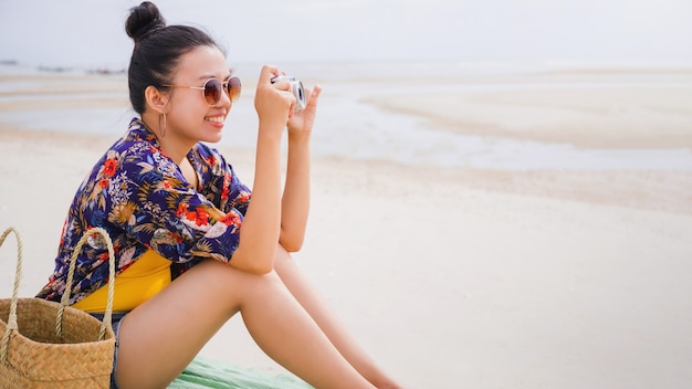 Asian traveller woman sit back and relax on the beach by the sea