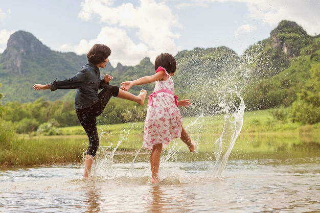 Asian two girls happy playing in the river. children having fun outdoors on summer lifestyle