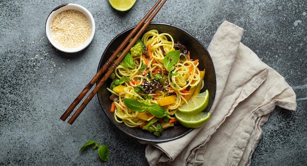 Asian vegetarian noodles with vegetables and lime in black