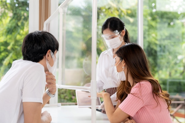 Asian waitress wear face mask and face shield using tablet to show restaurant electronic menu