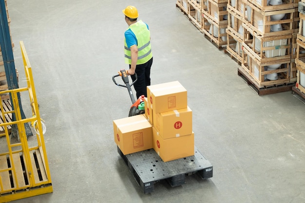 Asian warehouse worker pulling pallet truck Warehouse asian worker working in warehouse stock.