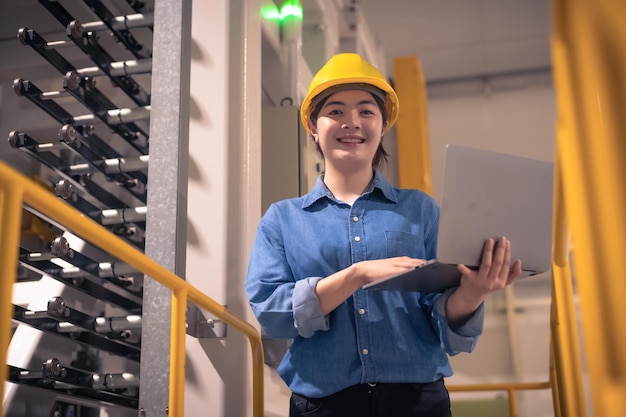 Asian woman are engineer factory inspecting machine in factory with computer Asian woman engineer working in factory concept