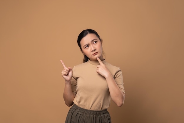 Asian woman bored and annoyed feel confuse standing isolated on beige background