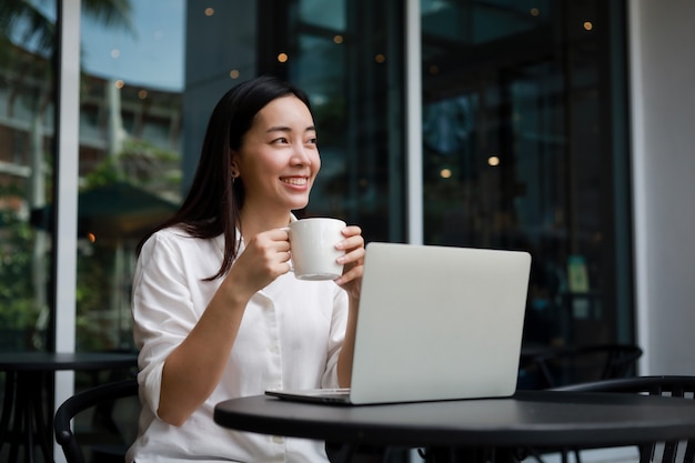 Asian woman at a cafe working on a laptop