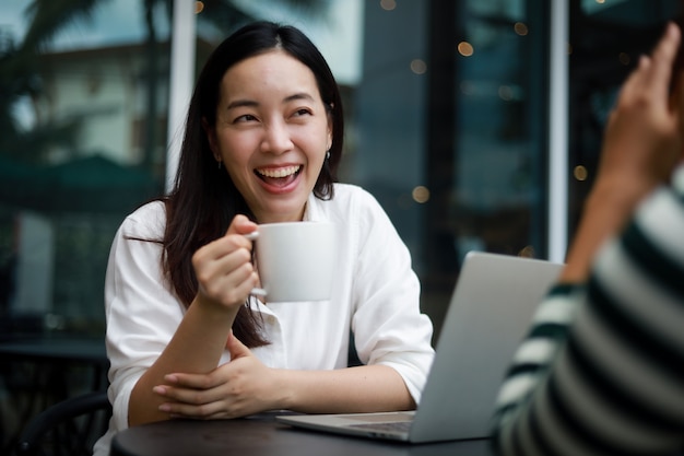 Asian woman at a cafe working on a laptop