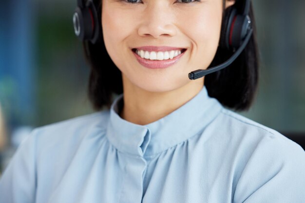 Asian woman call center employee and smile with face communication and CRM headset with mic and closeup Contact us customer service or telemarketing happy female consultant and help desk