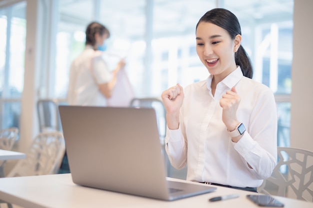 Asian woman celebrate with laptop, success happy pose.