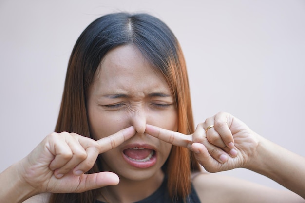 Asian woman covering her nose from bad smell with her hands