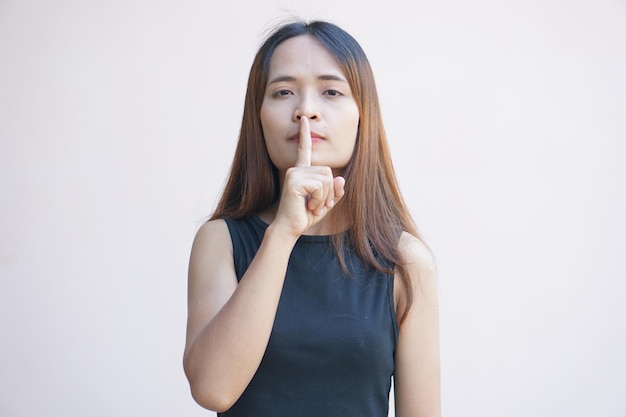 Asian woman covers her mouth with her finger