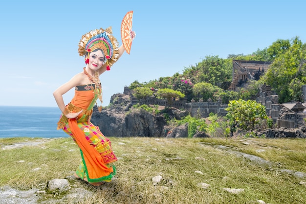 Asian woman dancing Balinese traditional dance (Kembang Girang dance) on the cliff