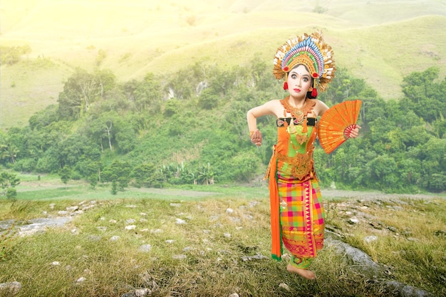 Asian woman dancing Balinese traditional dance (Kembang Girang dance) on the field