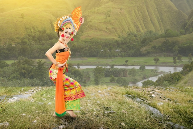 Asian woman dancing Balinese traditional dance (Kembang Girang dance) on the field