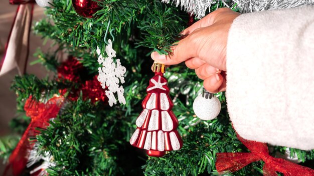 Asian woman decorating christmas tree with white modern element in room house