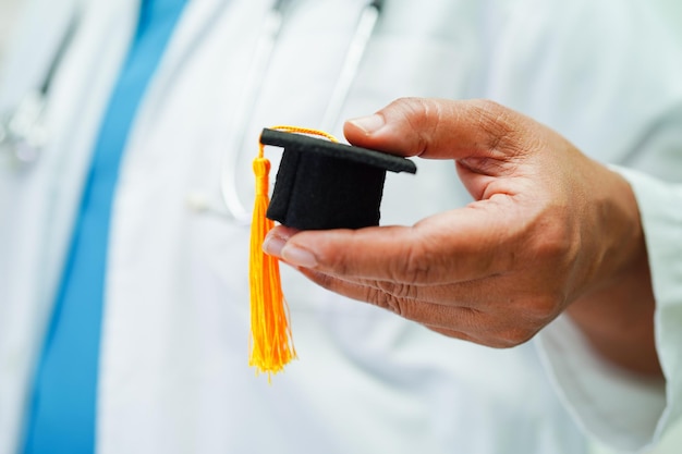 Asian woman doctor holding graduation hat in hospital Medical education concept