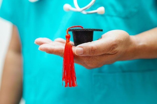 Asian woman doctor holding graduation hat in hospital Medical education concept