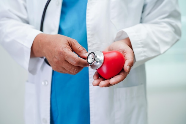 Asian woman doctor holding red heart for health in hospital