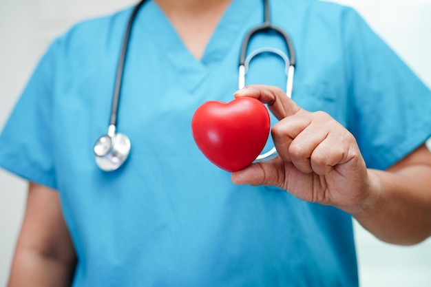 Asian woman doctor holding red heart for health in hospital