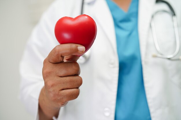 Asian woman doctor holding red heart for health in hospital