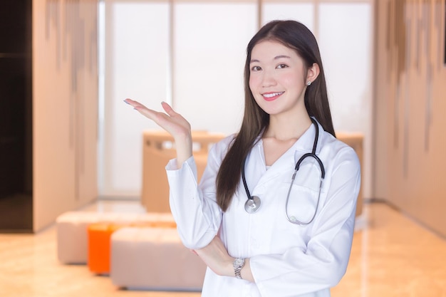 Asian woman doctor shows her hand to present something confidently in the hospital background