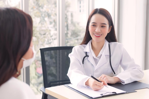 Asian woman doctor suggests healthcare solution to her patient elderly in examination room