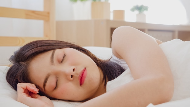 Asian woman dreaming while sleeping on bed in bedroom