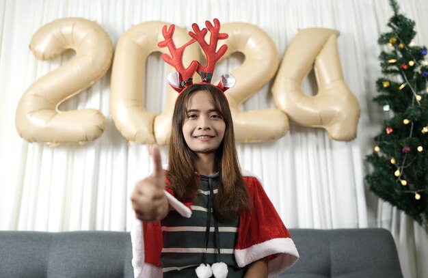 Asian woman dressed as a shanty Have fun celebrating Christmas 2024 Decorate and decorate the room with a Christmas tree and 2024 balloons