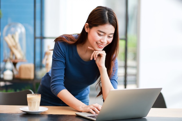 Asian woman drinking coffee and working with laptop computer